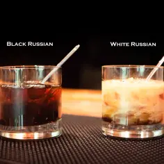Dwa drinki: ciemny Black Russian z lodem i jasny White Russian z mlekiem, każdy w szklance z rurką.